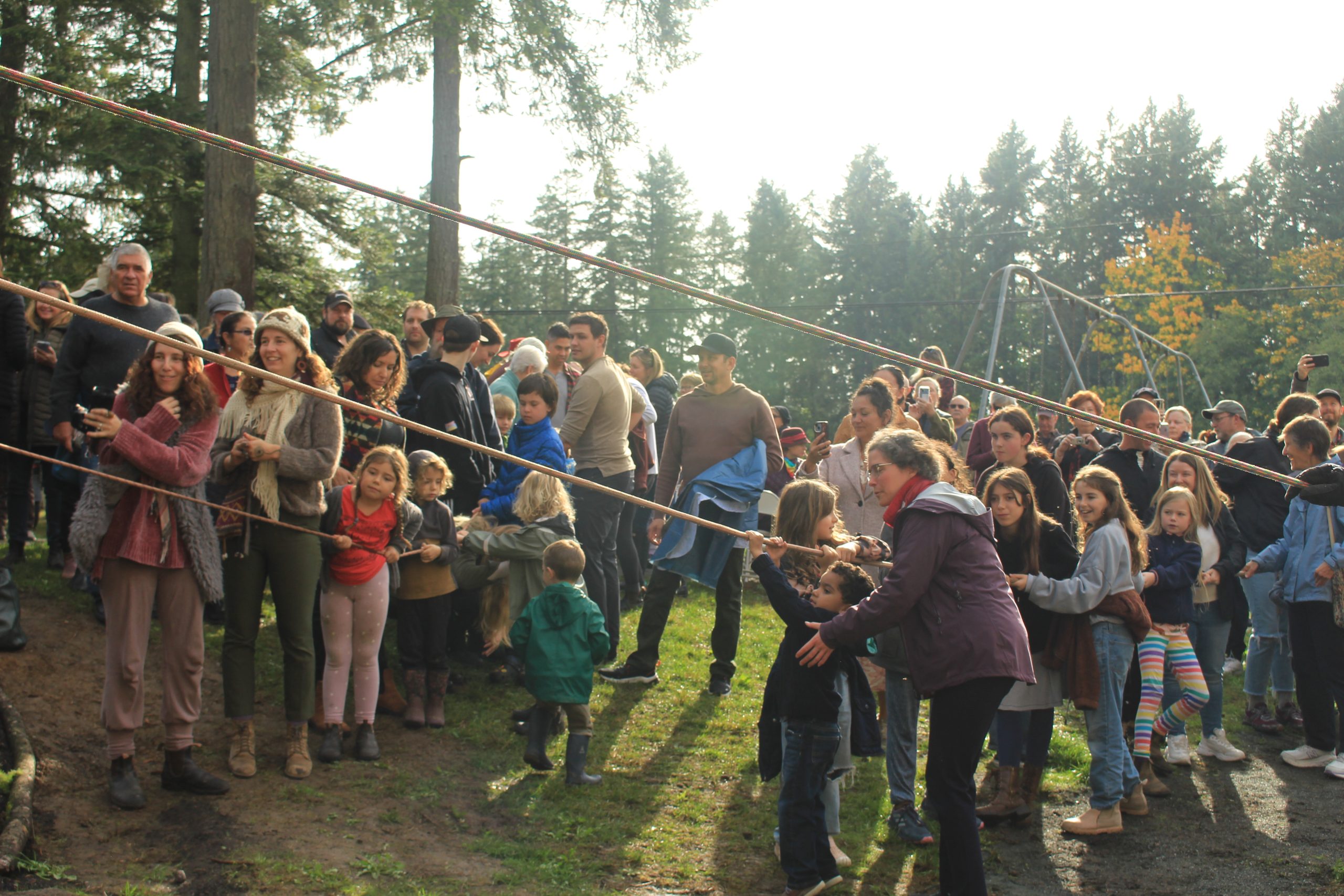 Community members pull on ropes that are running off frame to the left of the photo.