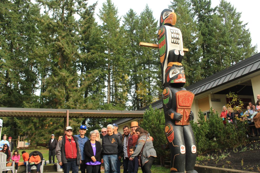 Rupert Scow and his family stand next to the newly-raised totem pole.